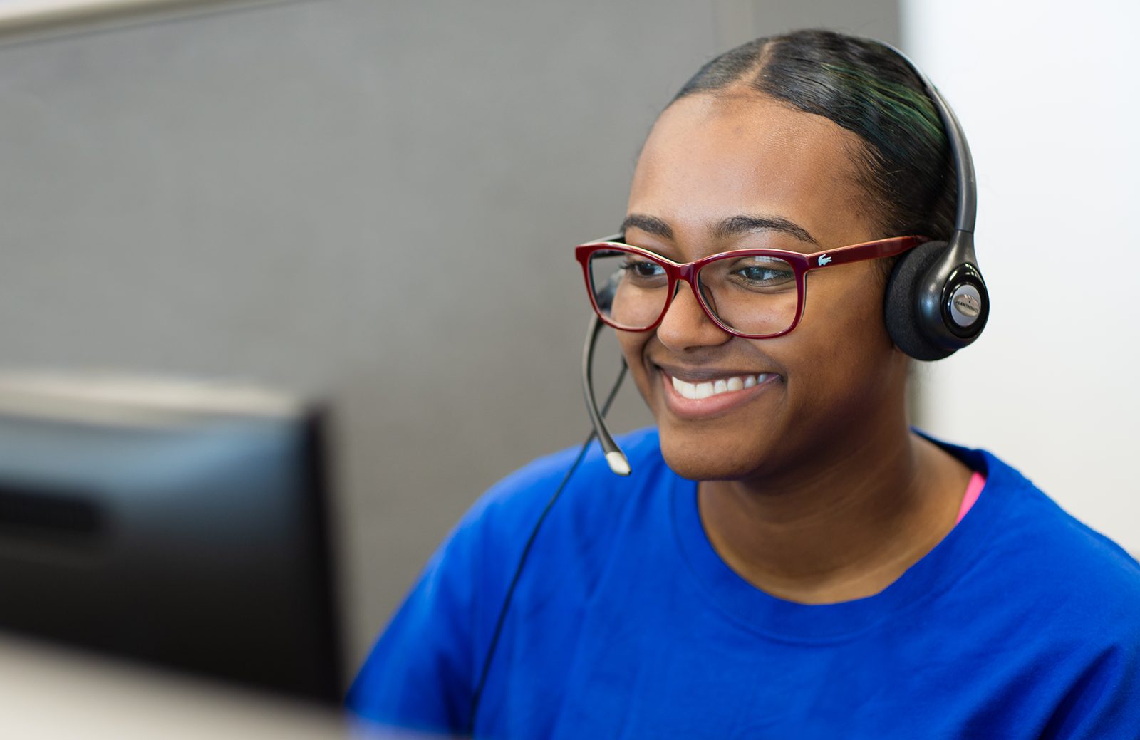 A United Way 211 specialist wearing a headset, smiling on a call