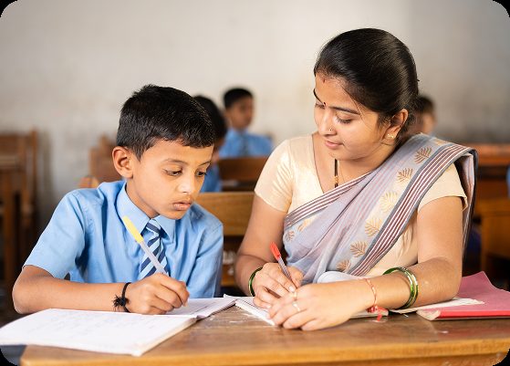 A teacher helping a student write at a classroom desk