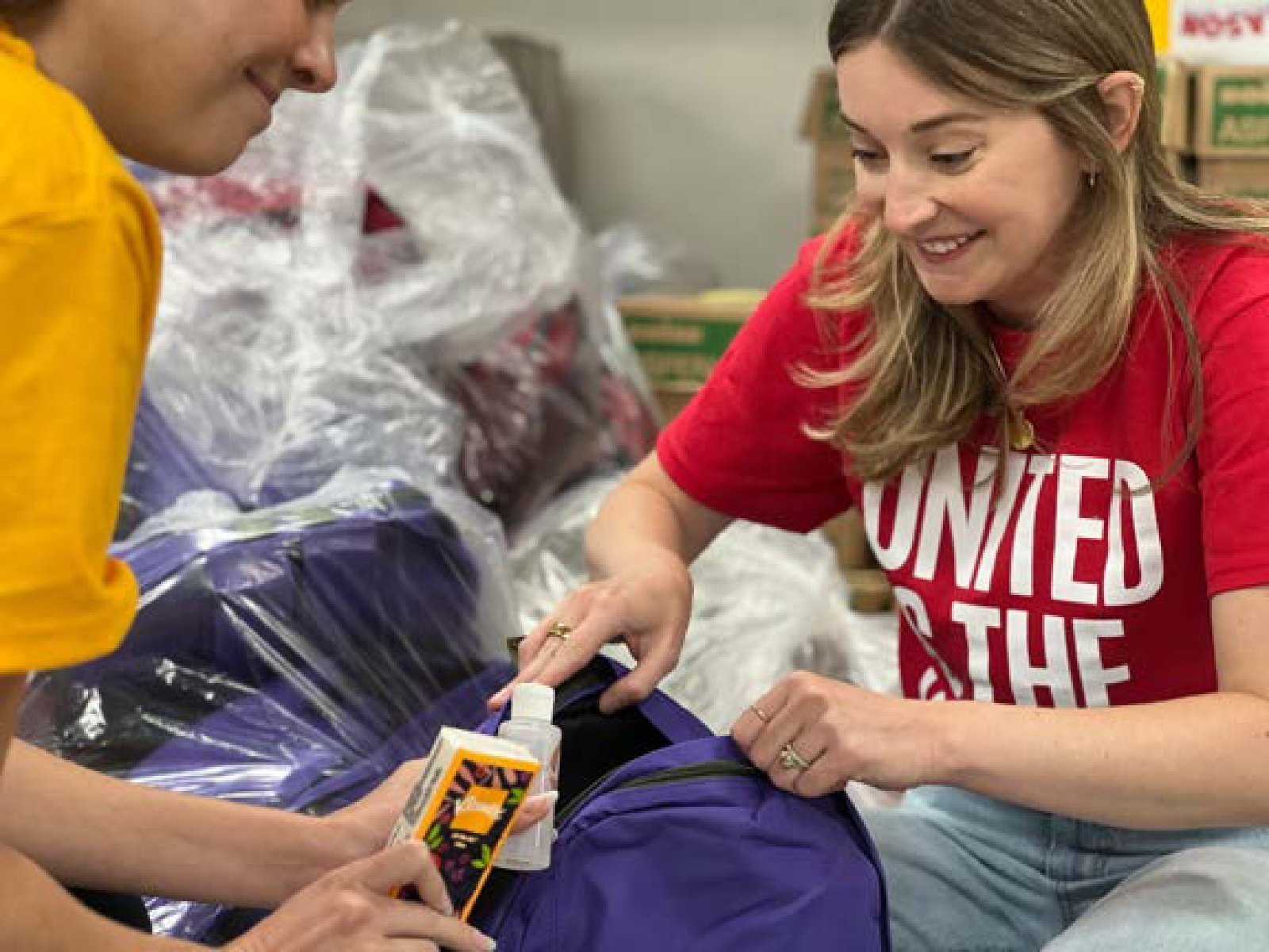 A volunteer packing school supplies into a backpack